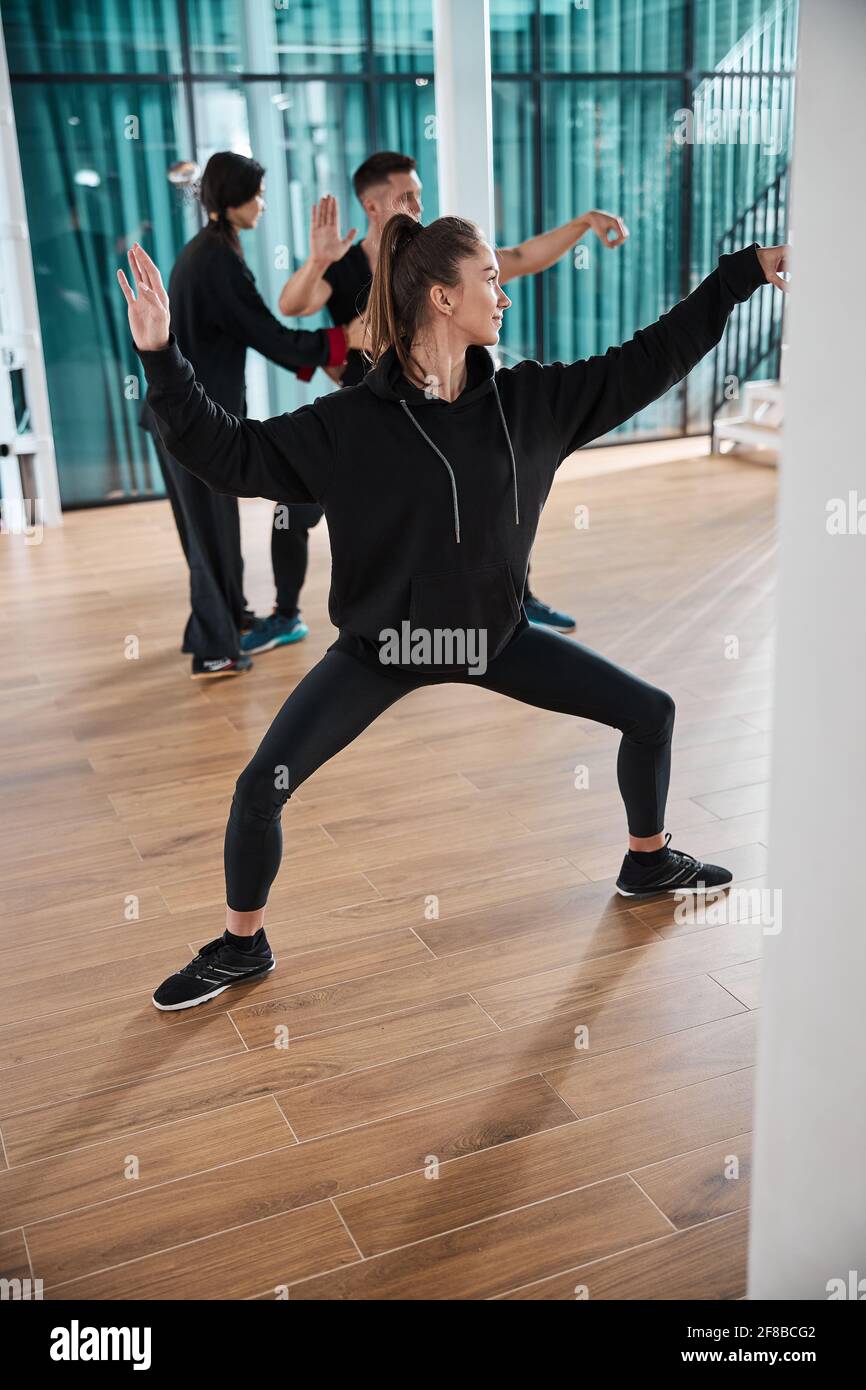 Junge Frau, die versucht, Tai Chi-Haltung zu zeigen Stockfoto