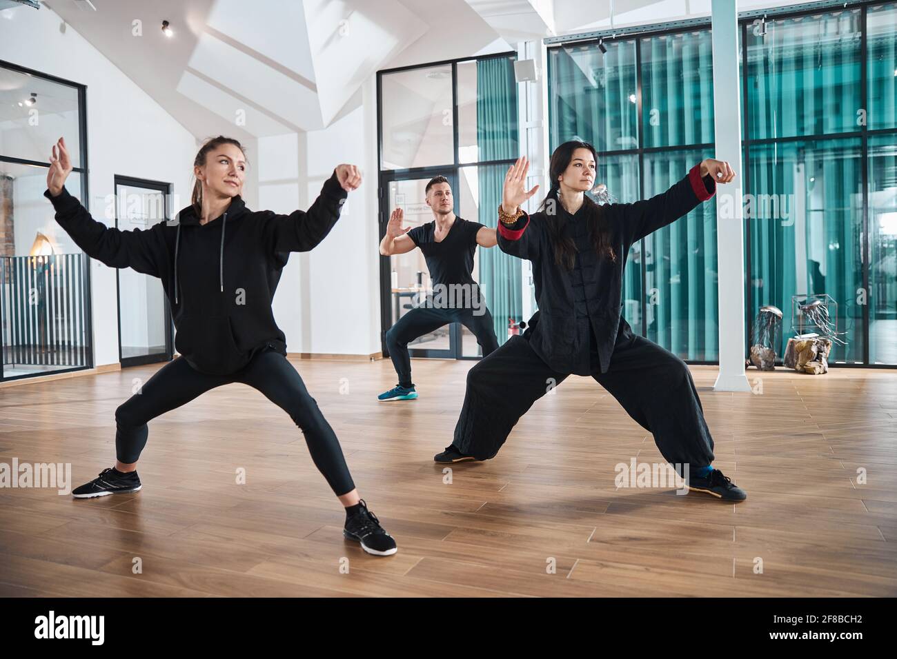 Der Meister zeigt zwei Erwachsenen die richtige Tai Chi-Form Stockfoto