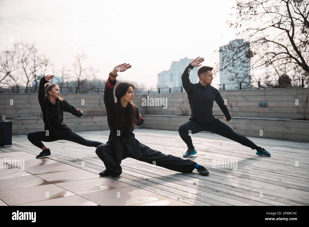 Drei Personen machen einen tiefen Ausfallschritt mit Tai Chi Stockfoto