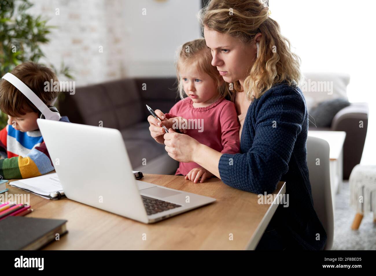 Mutter im Heimbüro mit kleiner Tochter auf dem Schoß Stockfoto