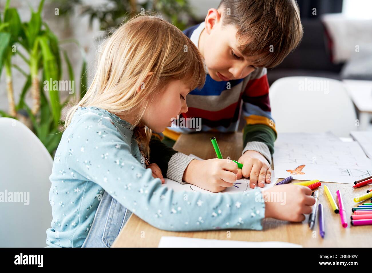 Nahaufnahme eines Bruders, der seiner Schwester bei ihren Hausaufgaben hilft Stockfoto