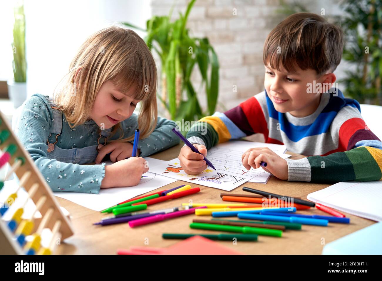Lächelndes Geschwisterchen, das gemeinsam Hausaufgaben macht Stockfoto