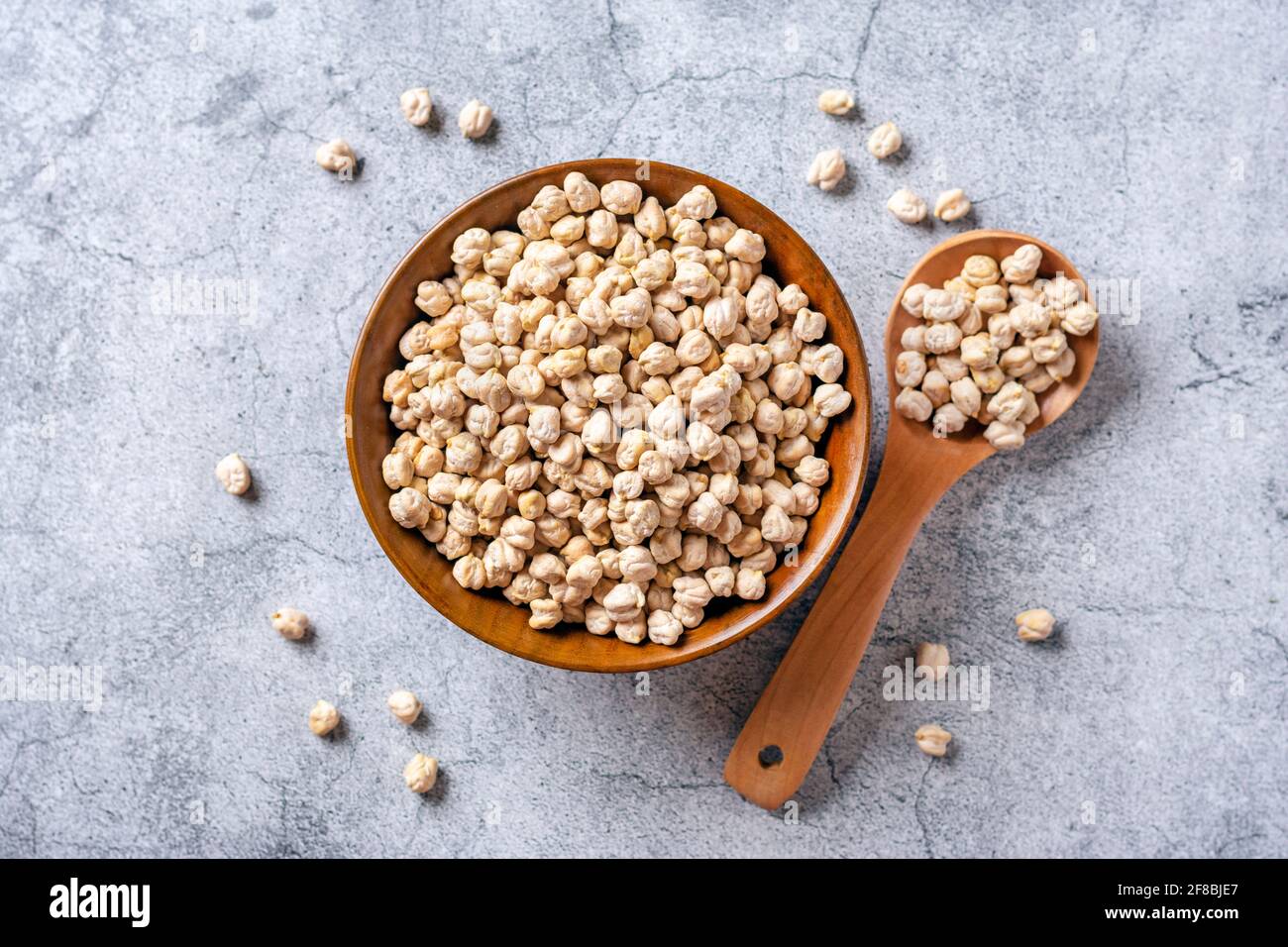 Trockene Kichererbsen in Holzschüssel auf Betongrund gesundes Essen, pflanzliches Protein-Konzept Draufsicht Flat Lay. Stockfoto