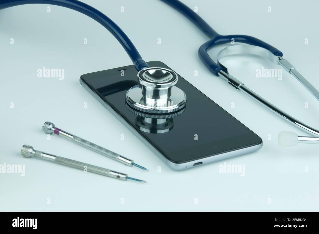 Stethoskop auf dem Smartphone auf blauem Hintergrund. Reparatur- und Servicekonzept per Telefon. Konzept eines Funktionszustands des Geräts. Stockfoto