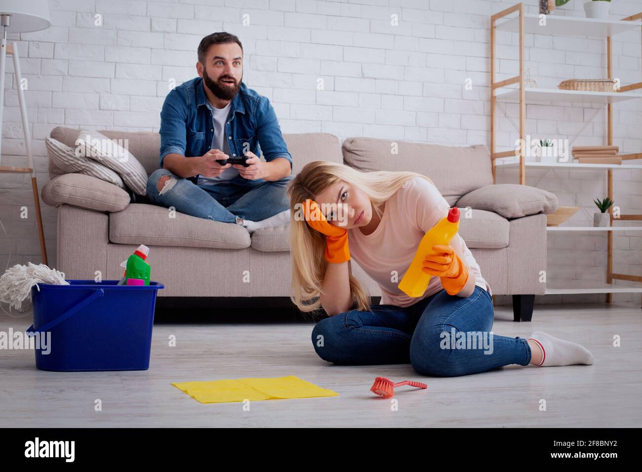 Chauvinismus und Sexismus zu Hause Konzept. Depressive Dame Hausfrau sitzt auf dem Boden Stockfoto