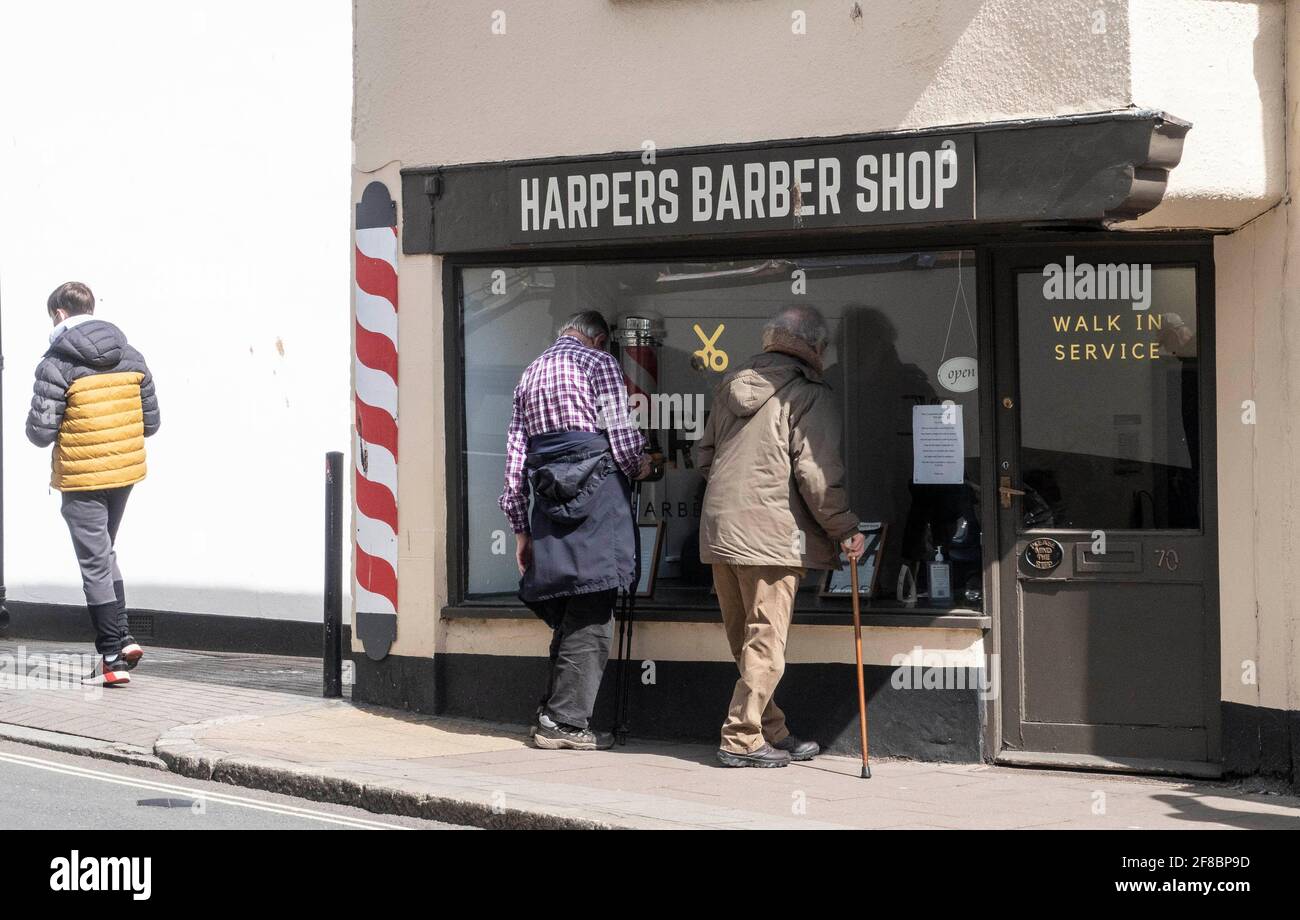 Sidmouth, Devon, 13. April 2021 nach der Lockerung der Zwangsbeschränkungen bildet sich vor einem Friseurladen in Sidmouth High Street, Devon, eine Schlange von Männern, Quelle: Photo Central/Alamy Live News Stockfoto