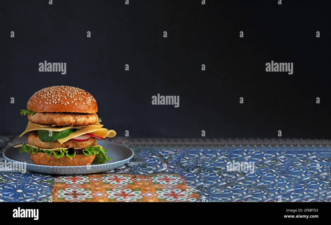Klassischer Hamburger mit zwei Schnitzel auf einem Teller. Lebensmittelbanner mit Platz für Text. Hühnerkäserurger mit Käse, Salat, Rettich. Café-Menü. Lokales Essen. Hausgemachtes Rezept. Stockfoto