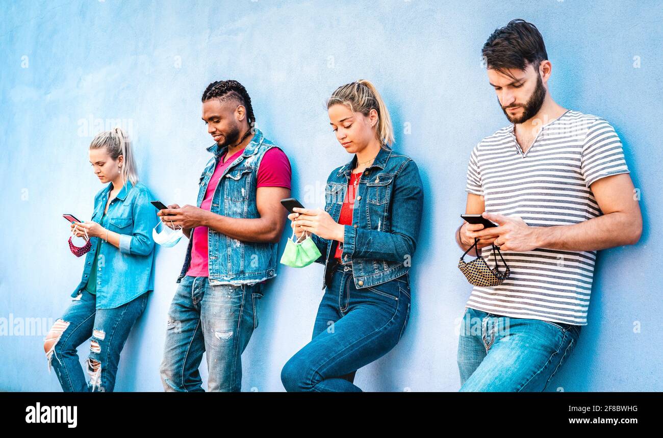 Multirassische Menschen tragen eine Maske mit offenem Gesicht und nutzen die Tracking-App mit Mobile Smartphones - Junge Freunde aus dem Milenial, die sich Inhalte ansehen Soziale Medien Stockfoto