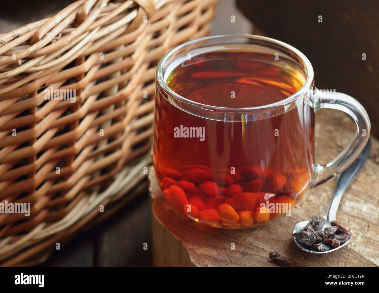 Goji-Beerentee in einer Glasschale auf rustikalem Holz mit Weide in der Nähe, Nahaufnahme, Naturheilkunde, Naturmedizin, ayurveda-Konzept, Rustikal, ländlich, langsam l Stockfoto