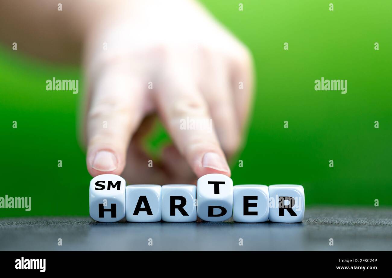 Die Hand dreht Würfel und ändert das Wort „härter“ in „marter“. Stockfoto