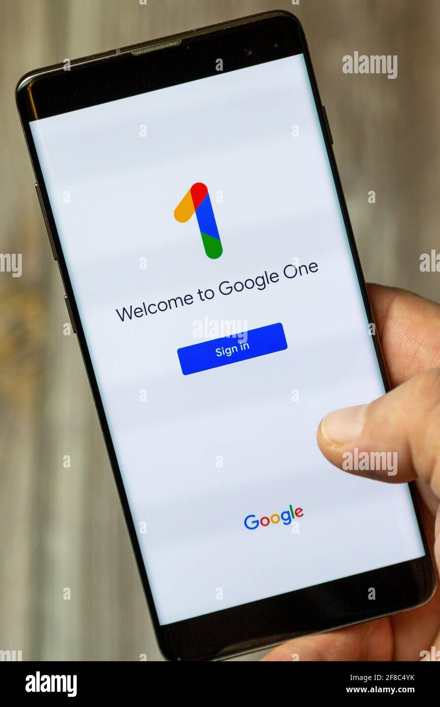 Ein Mobiltelefon oder Mobiltelefon, das von einem gehalten wird Hand mit der Google One App auf dem Bildschirm geöffnet Stockfoto