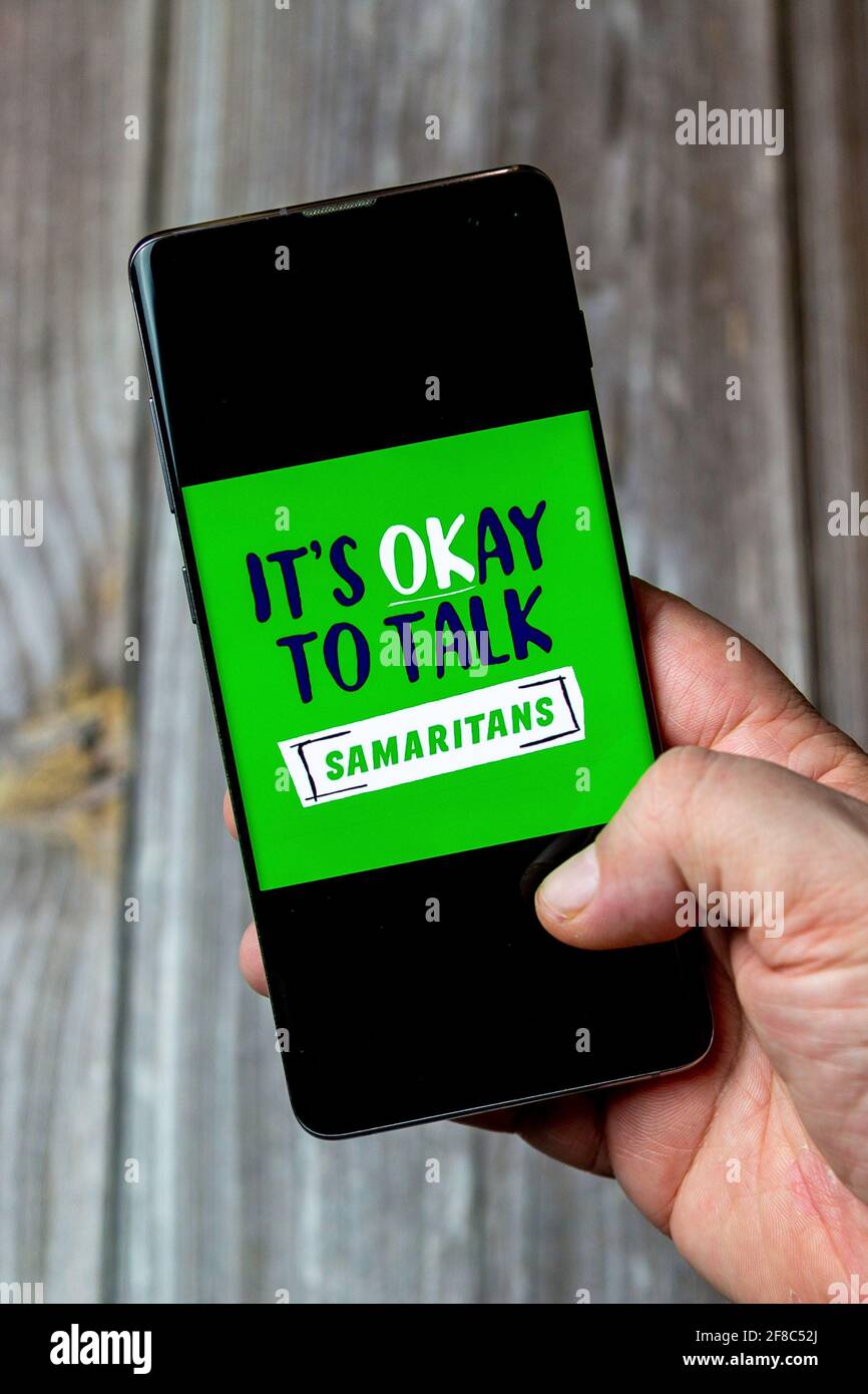 Ein Mobiltelefon oder Mobiltelefon, das in einem gehalten wird Hand mit dem Samaritans-Logo auf dem Bildschirm geöffnet Stockfoto