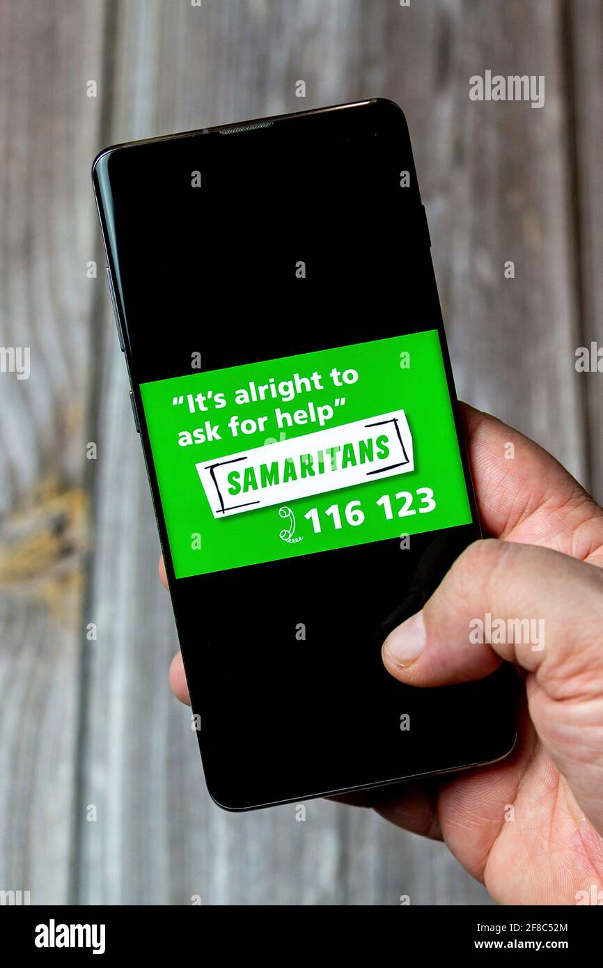 Ein Mobiltelefon oder Mobiltelefon, das in einem gehalten wird Hand mit dem Samaritans-Logo auf dem Bildschirm geöffnet Stockfoto