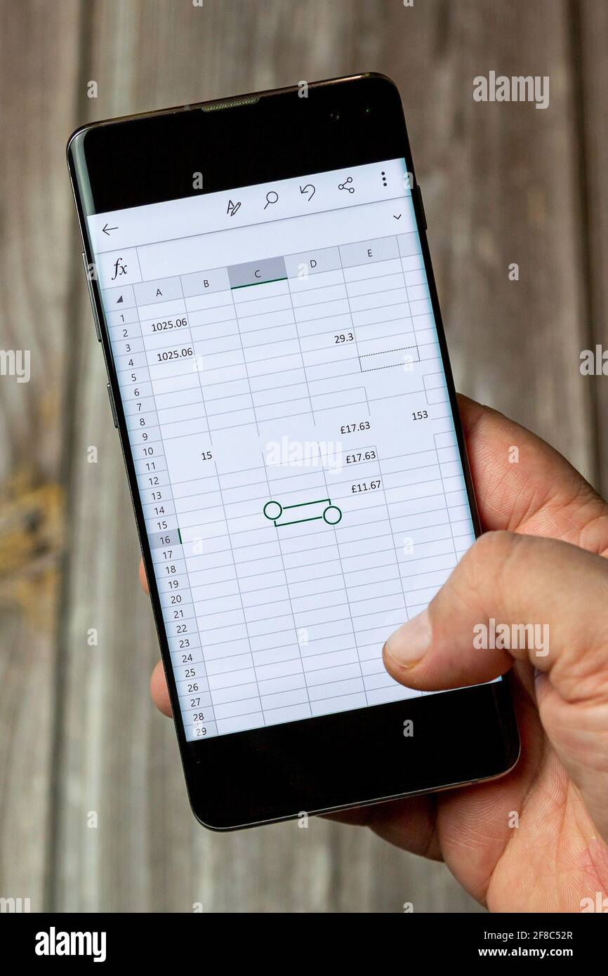 Ein Mobiltelefon oder Mobiltelefon, das in einem gehalten wird Hand mit einem microsft Excel-Dokument auf dem Bildschirm geöffnet Stockfoto