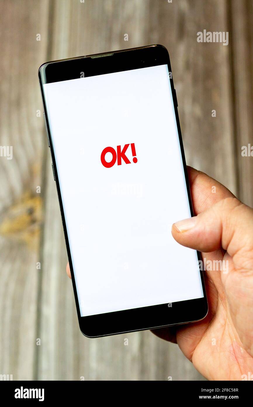 Ein Mobiltelefon oder Mobiltelefon, das in einem gehalten wird Hand mit der OK Magazin App auf dem Bildschirm geöffnet Stockfoto