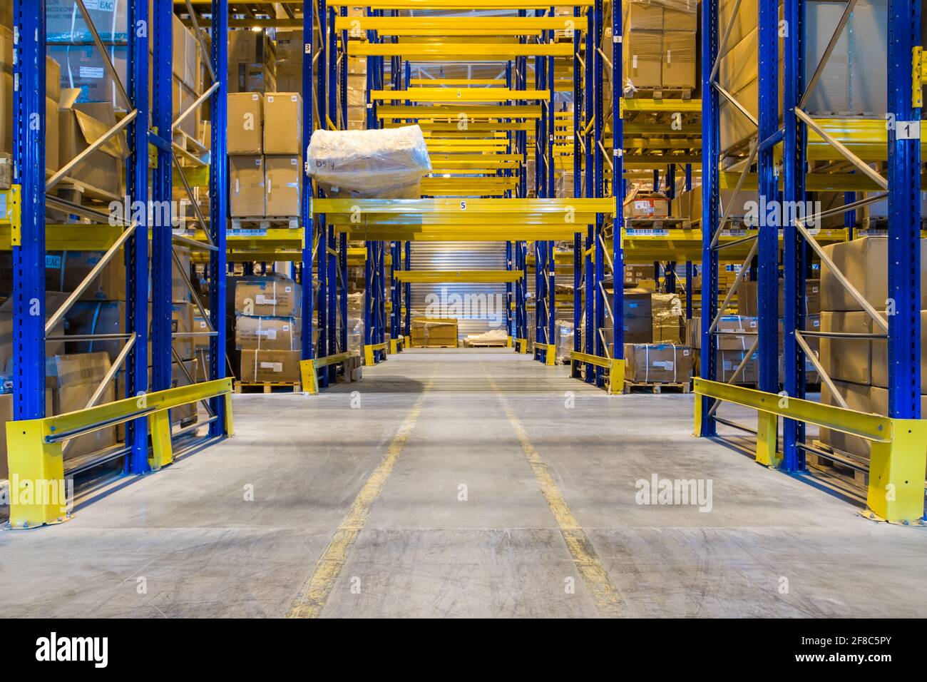 Innenraum eines modernen Lagerhauses mit Reihen und Waren Boxen auf hohen blau-gelben Regalen Stockfoto