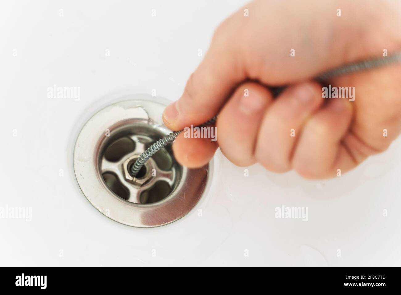 Klempner, der die Badewanne mit einer Abflussschlange entklumpt hat. Stockfoto