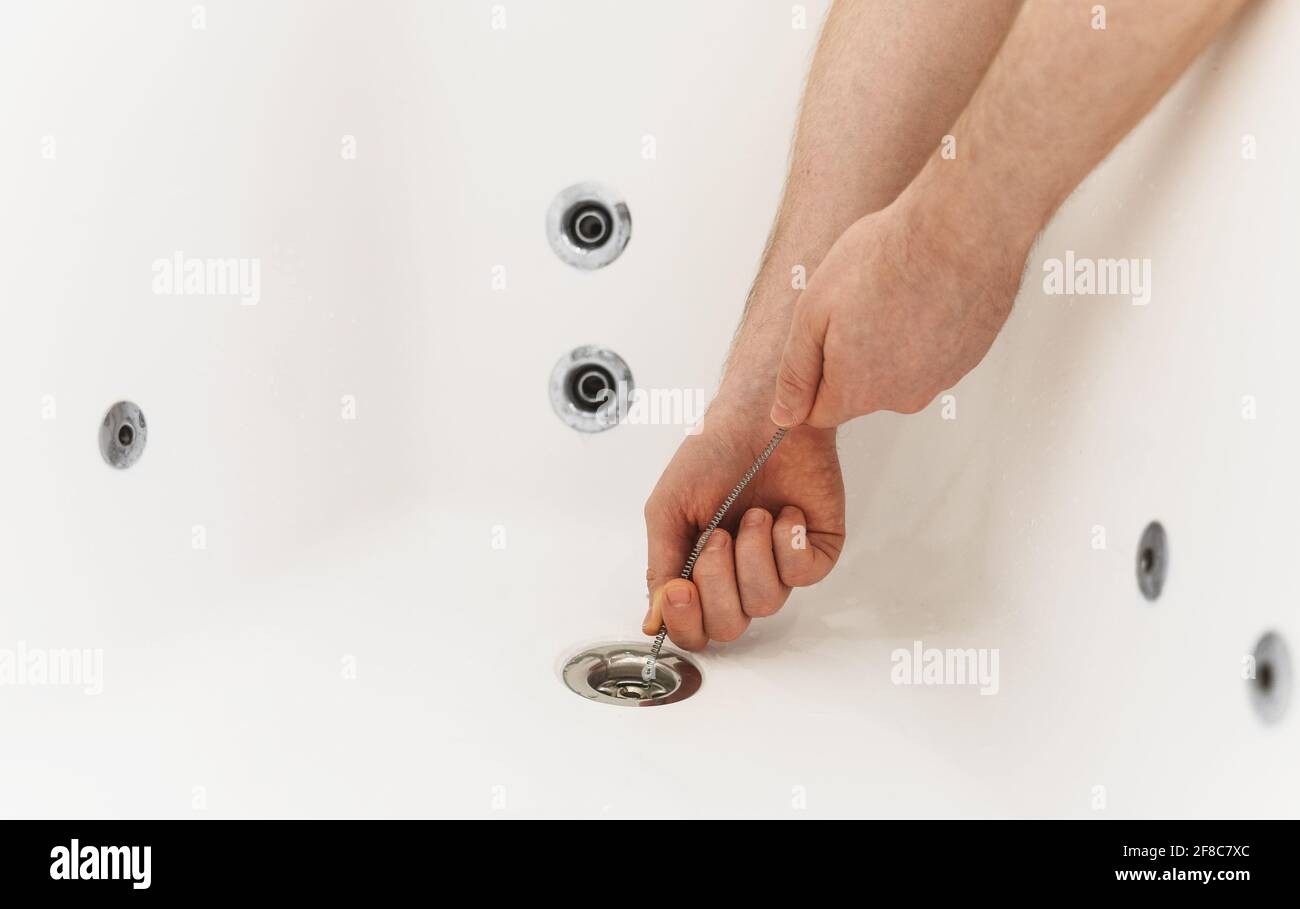 Klempner, der die Badewanne mit einer Abflussschlange entklumpt hat. Stockfoto