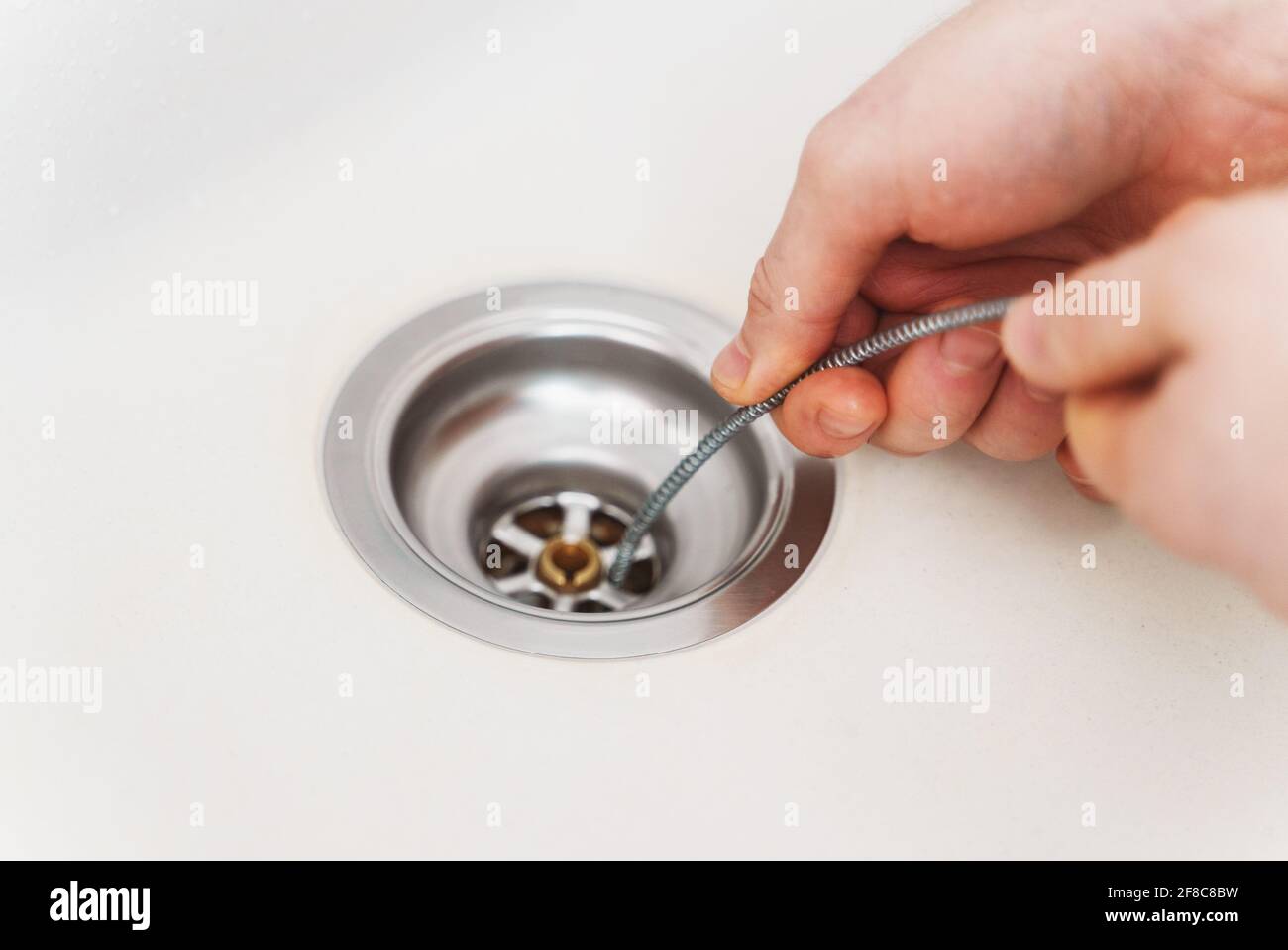 Klempner, der Abflussschlange verwendet, um das Spülbecken der Küche zu entverstopfen. Stockfoto