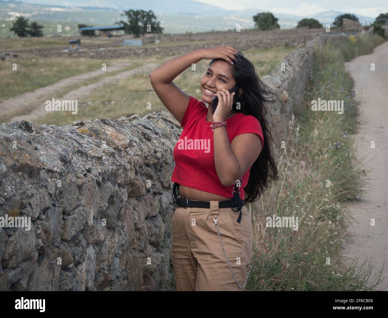 Horizont-Ansicht einer asiatischen Teenagerin, die mit ihrem Handy auf dem Land spricht. Stockfoto