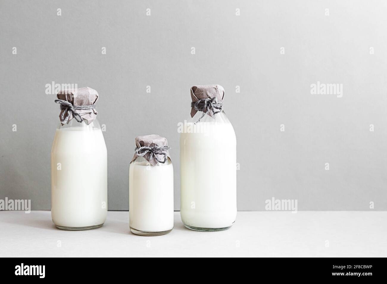 Minimale Standzeit von Milchflaschen auf hellem Hintergrund mit Platz für Kopien. Milchproduktion, Bio-Produkt. Das Konzept der gesunden Ernährung und Sustain Stockfoto