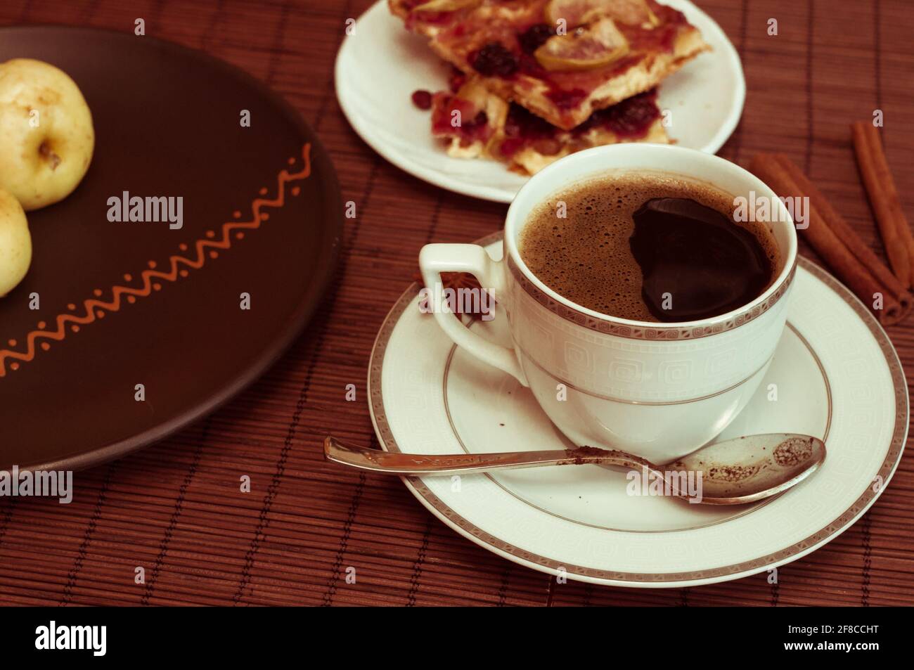 Stillleben - eine Tasse schwarzen Kaffee, hausgemachte Kekse mit Obst, gebackene Äpfel auf einer Bambusmatte Stockfoto