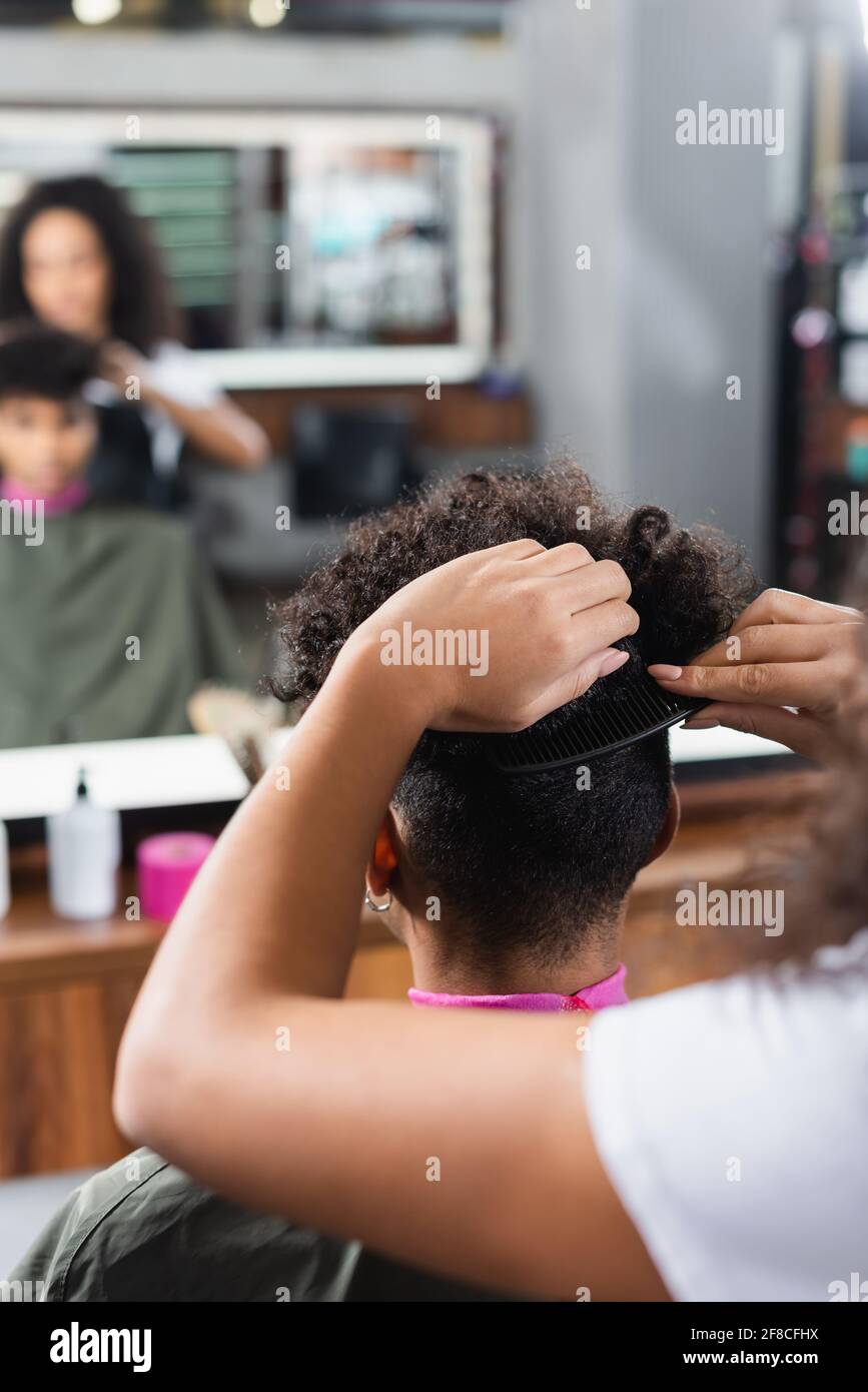 afroamerikanischer Friseur kämmt die Haare des Kunden im Salon Stockfoto