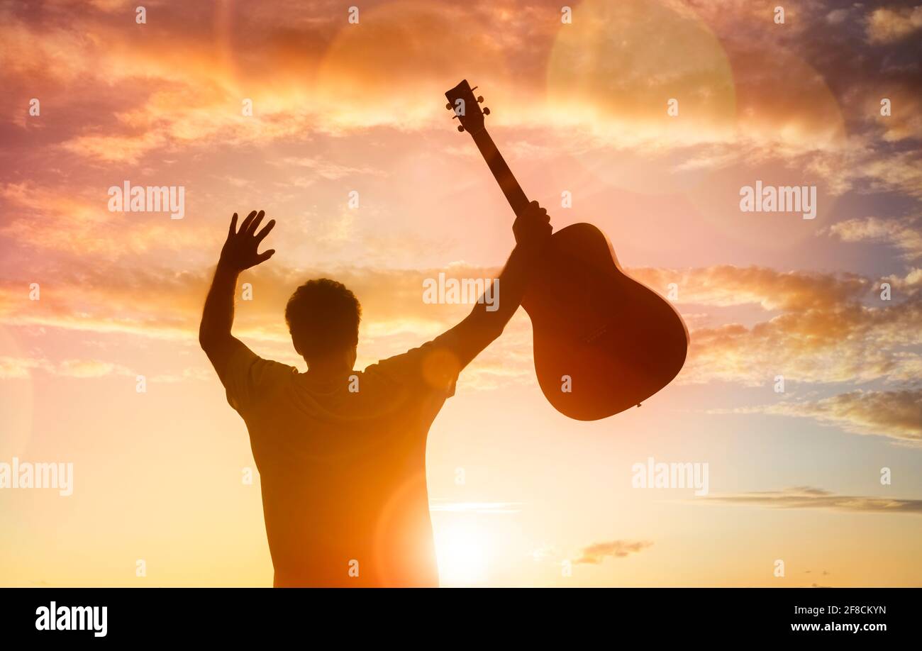 Silhouette des Gitarristen Musiker hält Gitarre gegen Sonnenuntergang Konzept für Religion oder Musikfestival Stockfoto