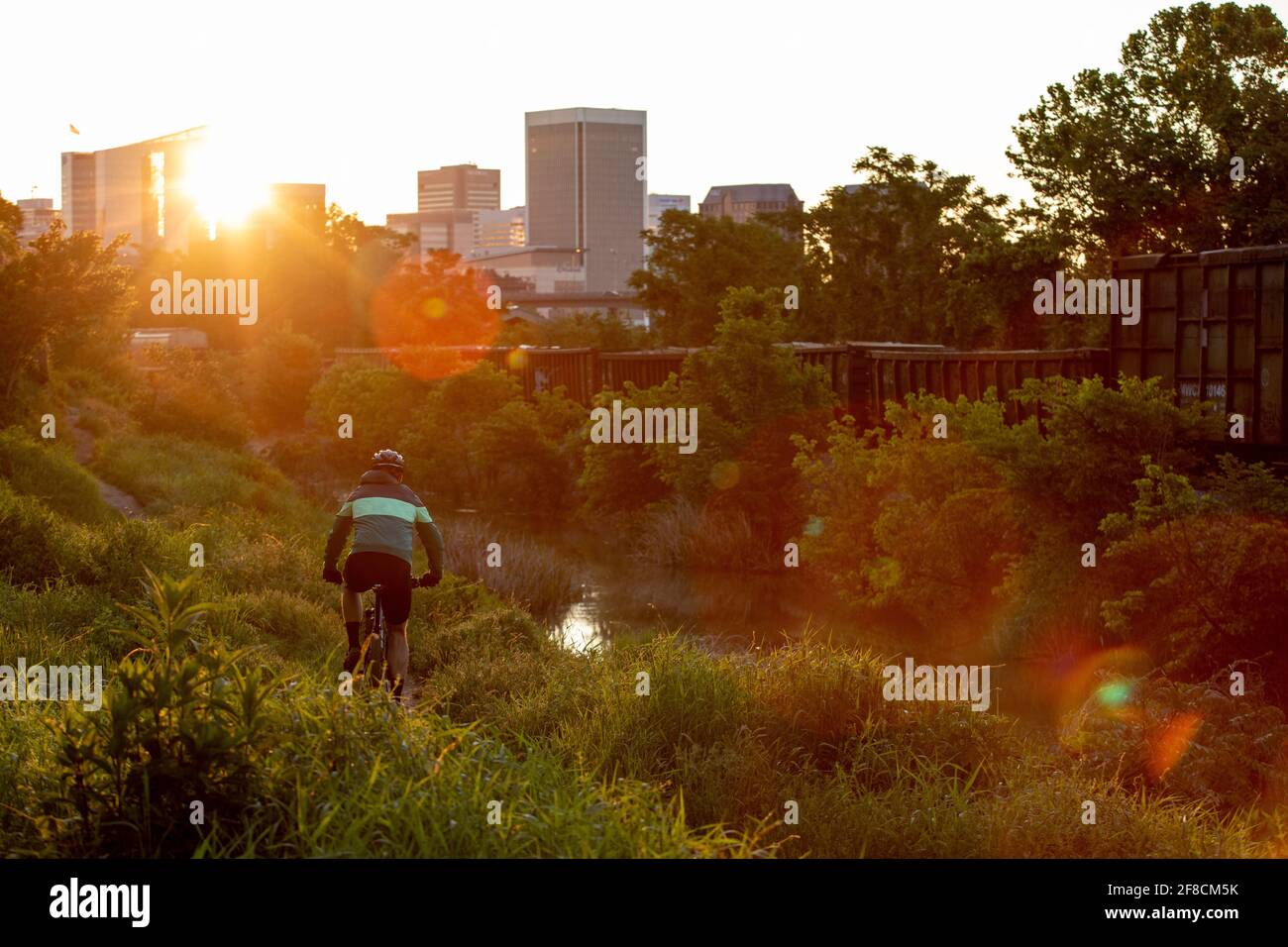 Mountainbiker bei Sonnenaufgang mit der Skyline von Richmond im Hintergrund. Stockfoto