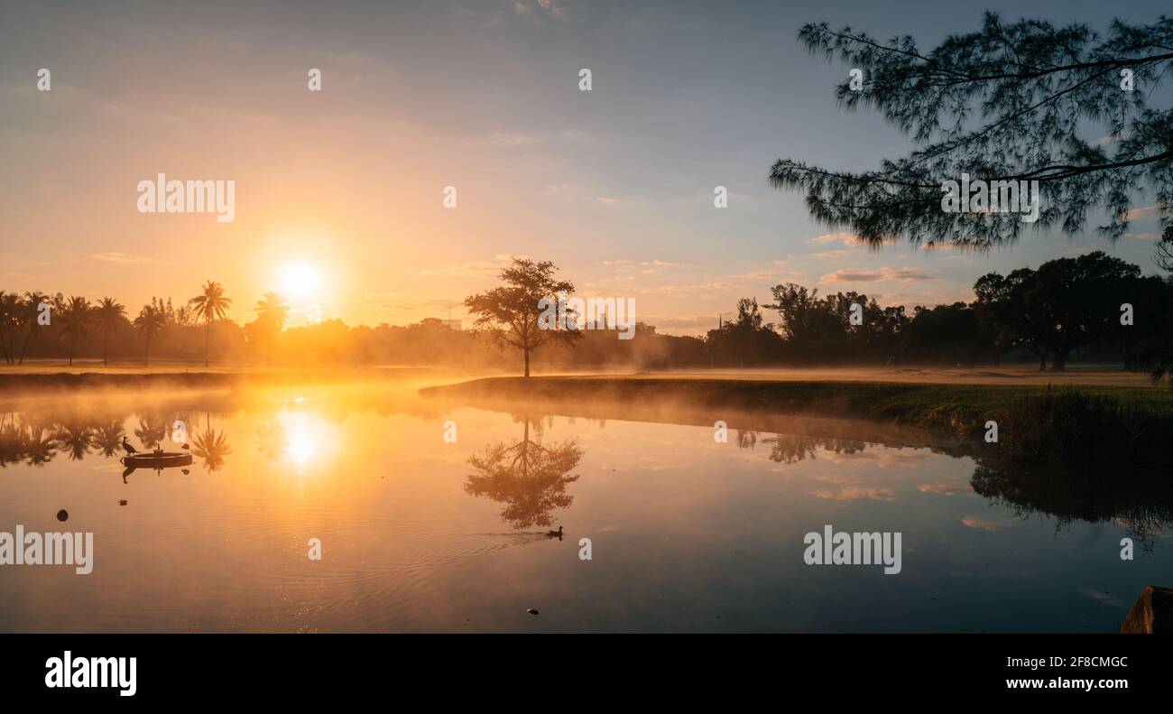 Schöner Sonnenaufgang auf dem See Reflexionen Baum Sonne Himmel niedlich Stockfoto