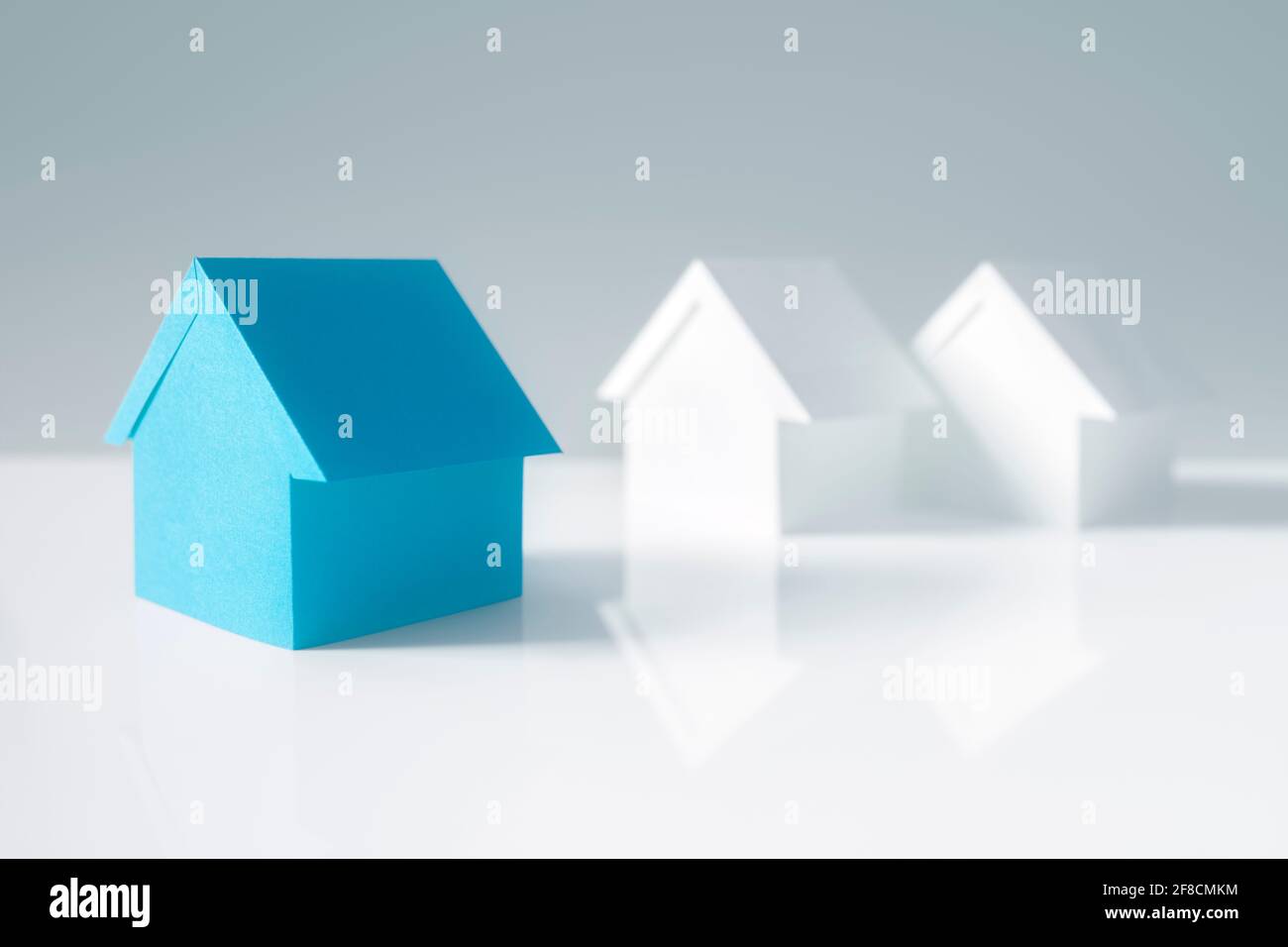 Auf der Suche nach Immobilien, Haus oder neues Zuhause, blaues Papierhaus, das sich heraussticht Stockfoto