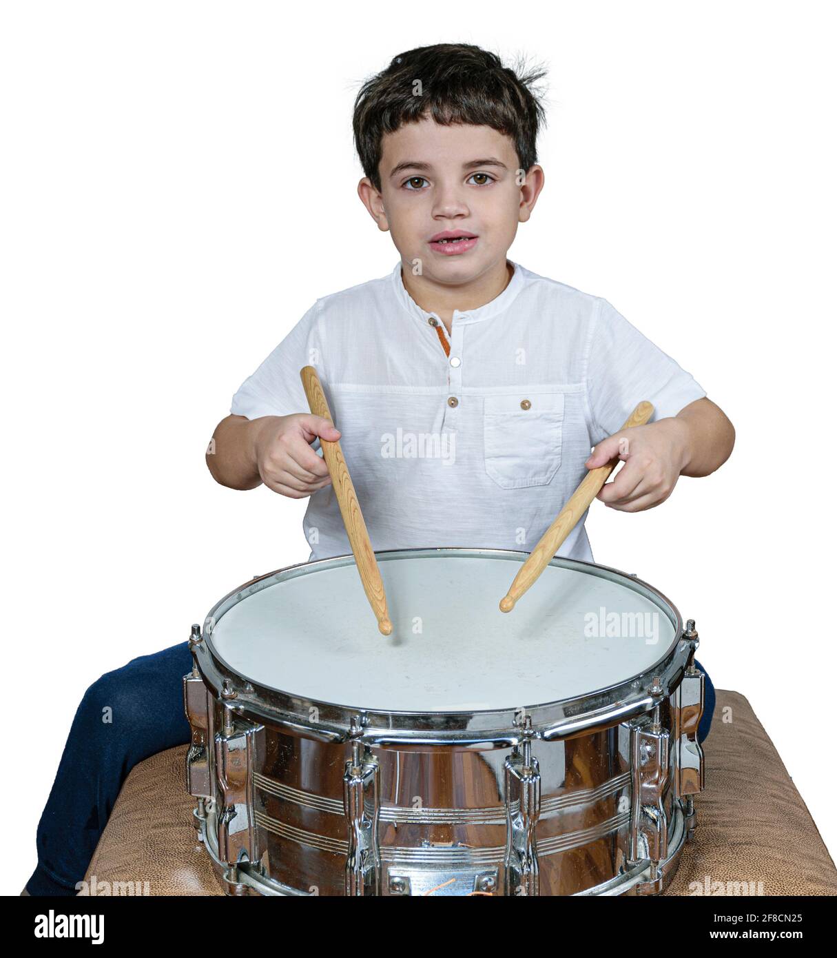 7-jähriges Kind starrte auf die Kamera und spielte Schlagzeug. Weißer Hintergrund. Stockfoto