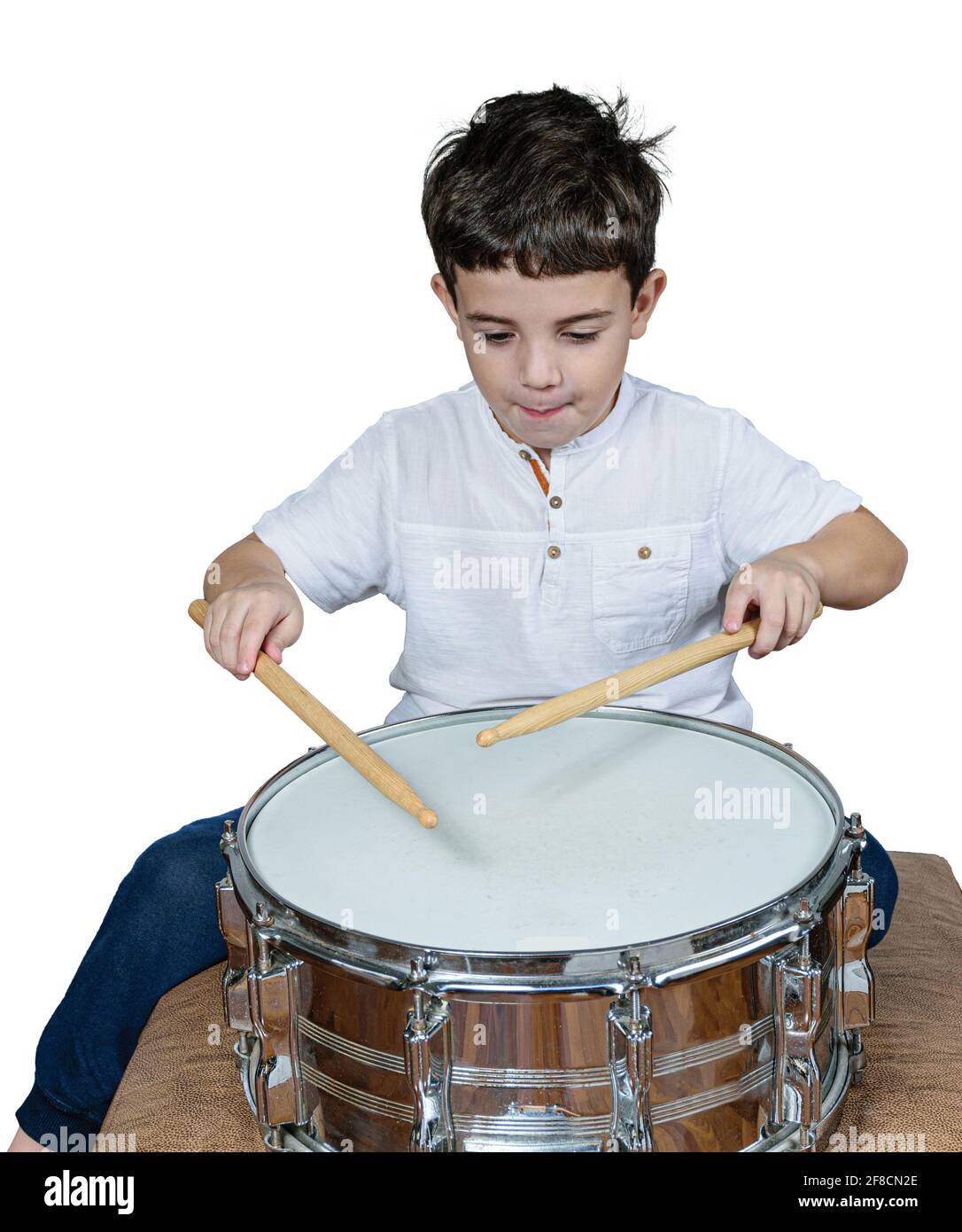 Das 7-jährige Kind konzentrierte sich und spielte Schlagzeug. Weißer Hintergrund. Stockfoto