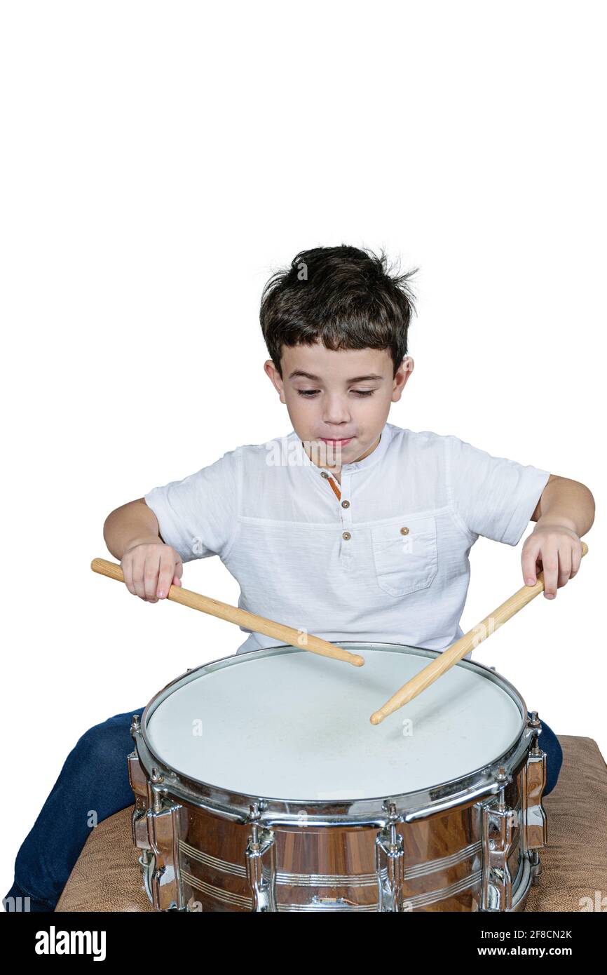 7 Jahre altes Kind, das Schlagzeug spielt und ein lustiges Gesicht macht. Weißer Hintergrund. Stockfoto
