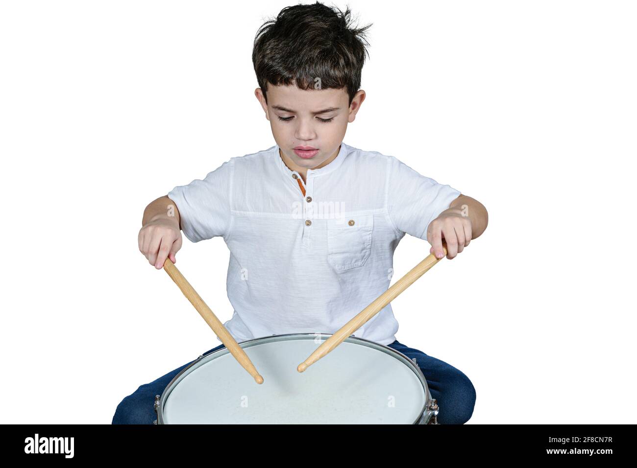 Das 7-jährige Kind konzentrierte sich auf seinen ersten Trommelunterricht. Weißer Hintergrund. Stockfoto
