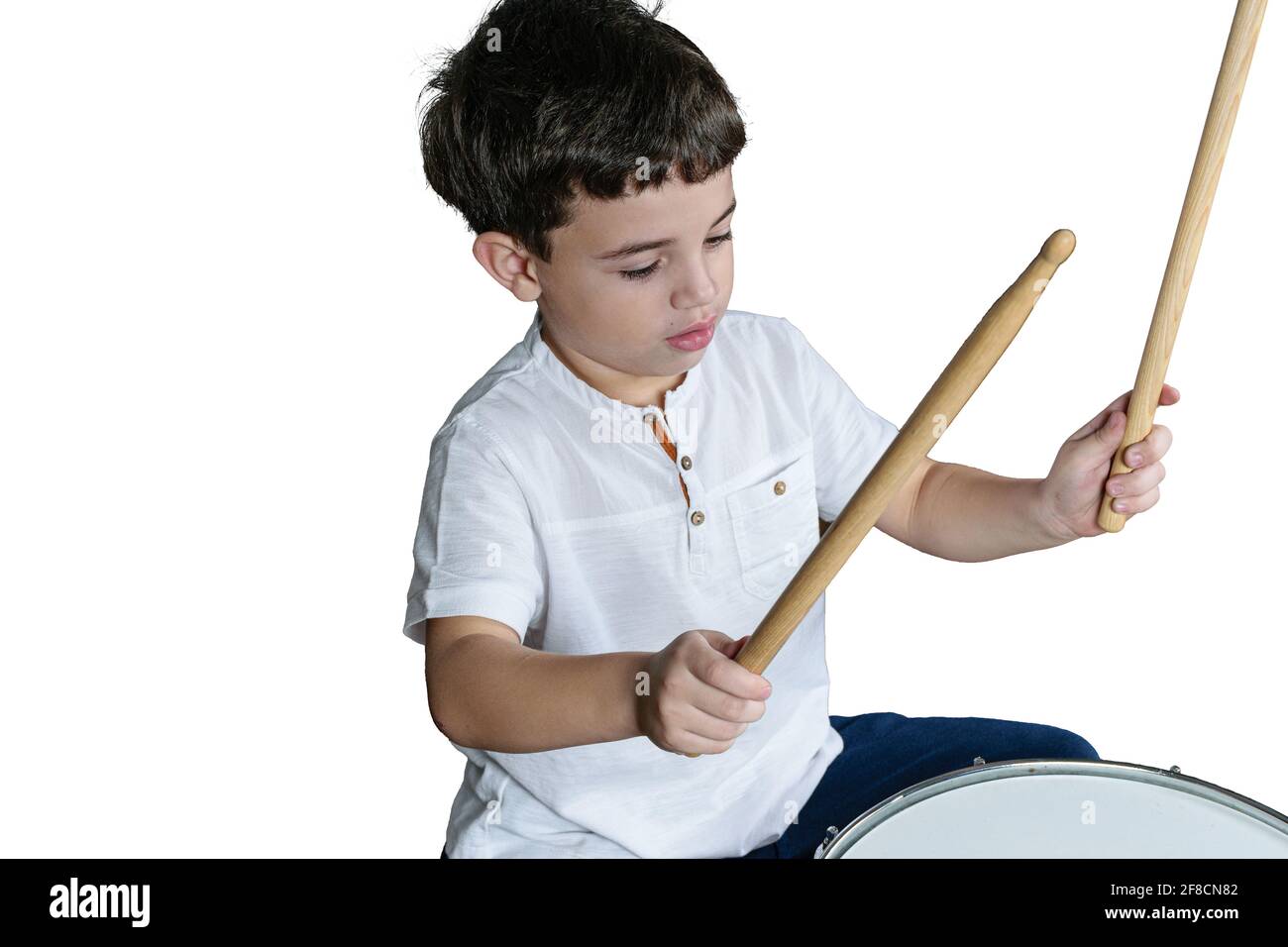 7-jähriges Kind mit seinen Dumsticks, die bereit sind, Schlagzeug zu spielen. Weißer Hintergrund. Stockfoto