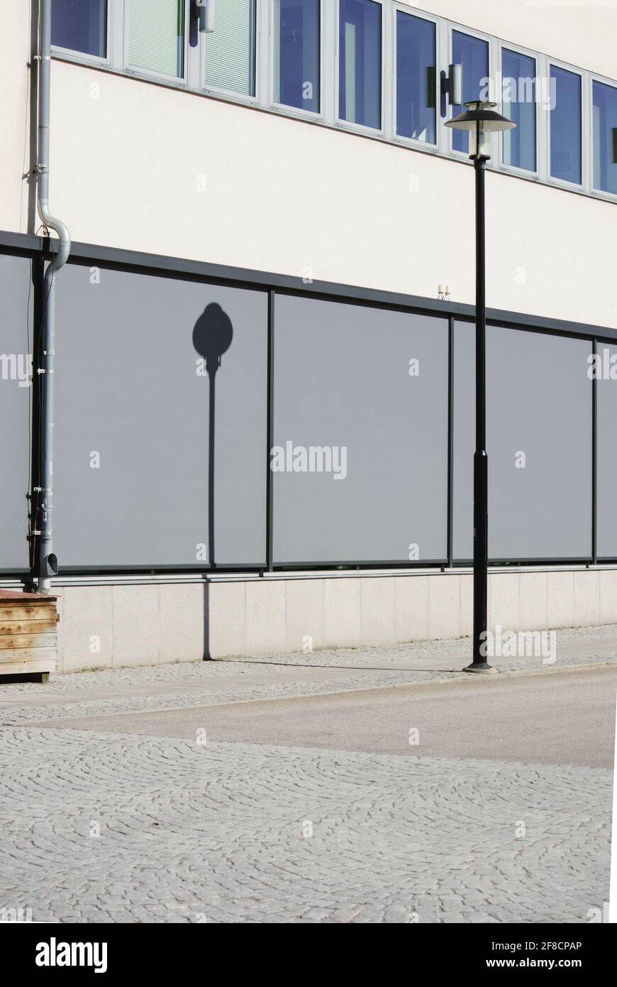 In Farbe und Form minimalistisches Foto einer Straßenlaterne und ihres Schattens auf einem modernen Gebäude. Stockfoto