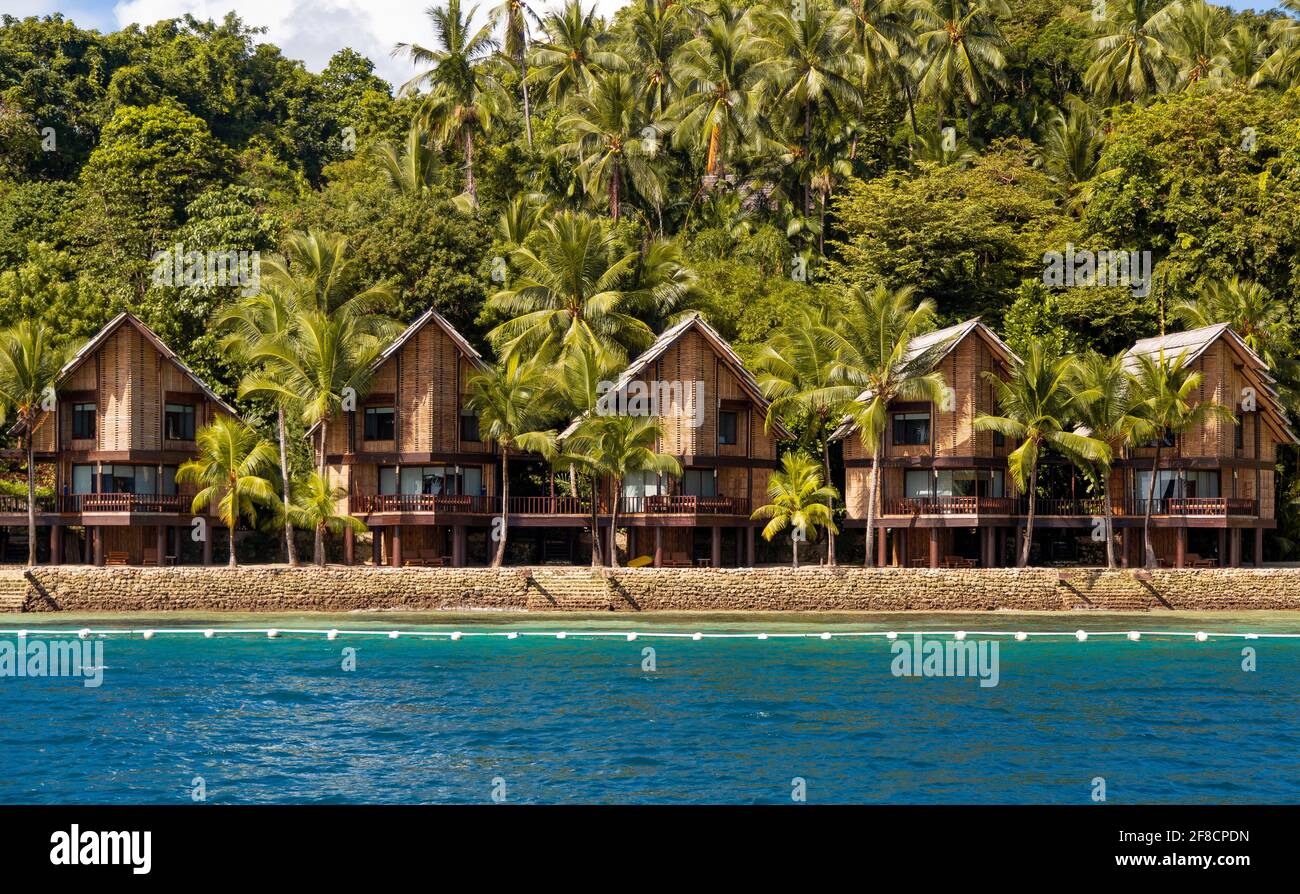 Wunderschönes Resort auf den Philippinen. Topische Hütten und Häuser am Strand mit blauem Meer und herrlichem sonnigem Wetter. Große, hohe Kokospalmen. Stockfoto