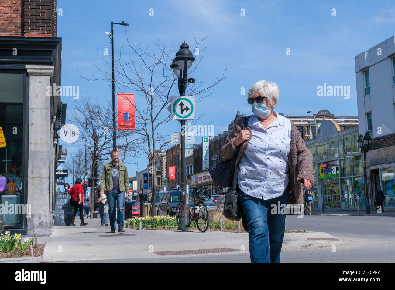 Montreal, CA - 11. April 2021: Fußgänger mit Gesichtsmaske zum Schutz vor COVID-19, der die Straße entlang geht Stockfoto