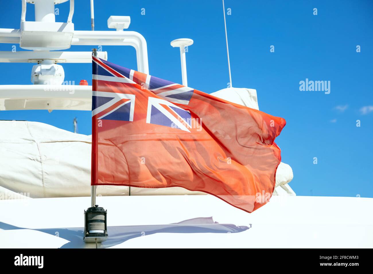 Die Flagge des Vereinigten Königreichs winkt auf dem Heck der Yacht. Red Duster ist ein britischer ziviler Fähnrich. Das britische Luxusboot liegt in einem Yachthafen. Blauer Himmel, Nahaufnahme Stockfoto