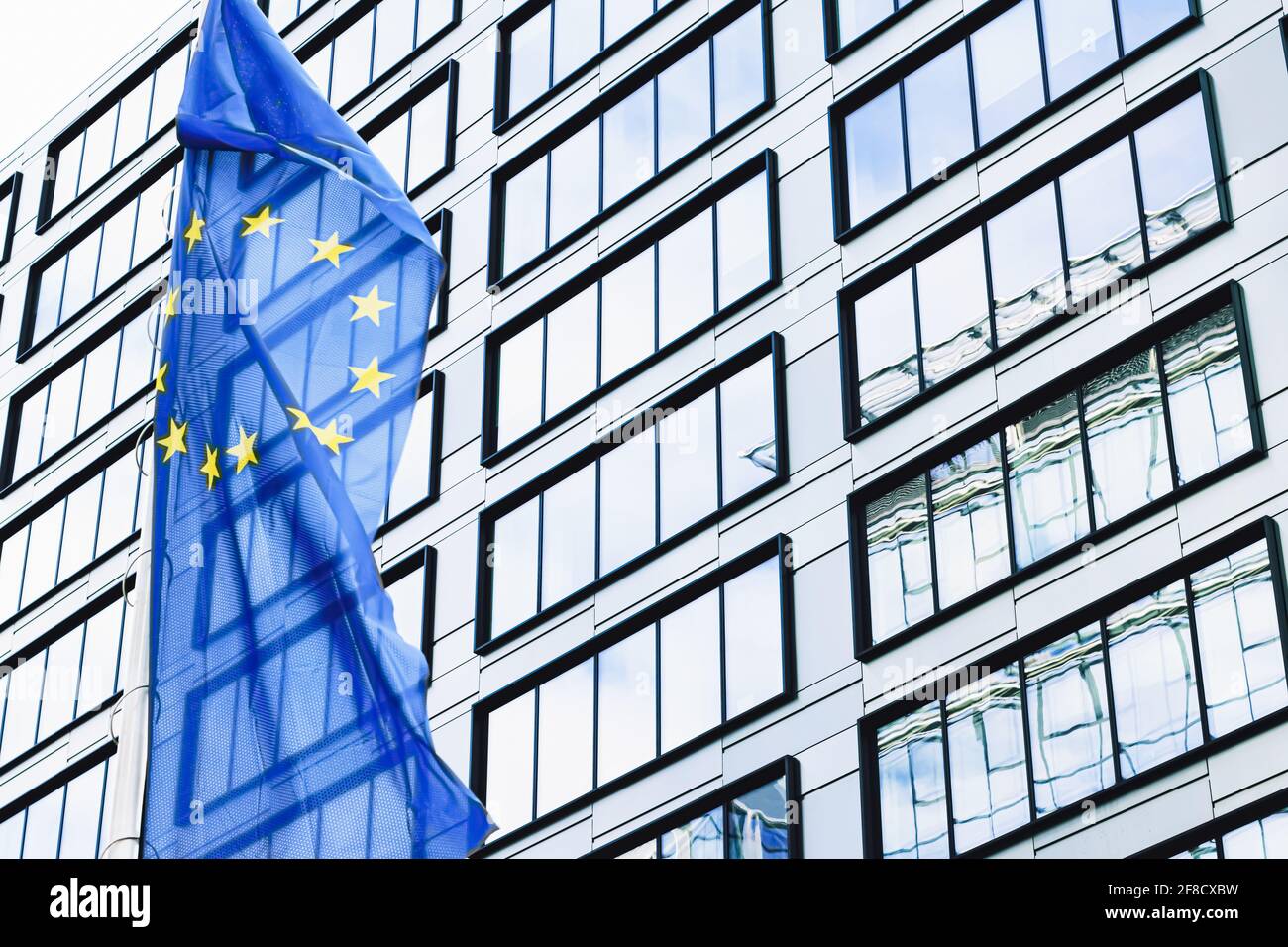 Die Flagge der Europäischen Union winkt vor dem modernen Bürogebäude, Symbol des EU-Parlaments, der Kommission und des Rates Stockfoto