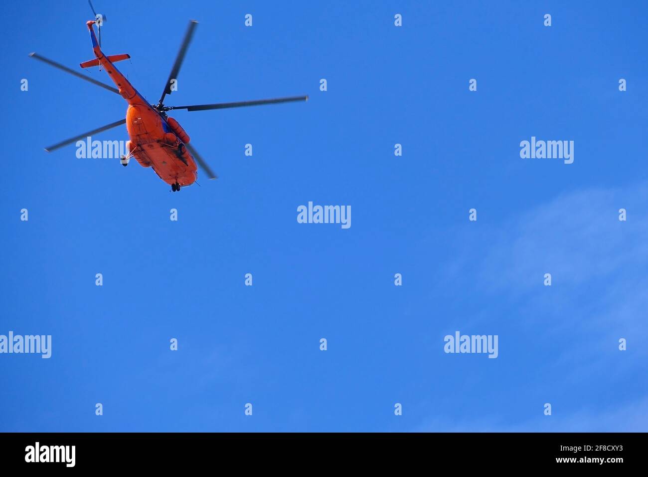 Ein roter Hubschrauber fliegt hoch am blauen Himmel, Aviation. Stockfoto