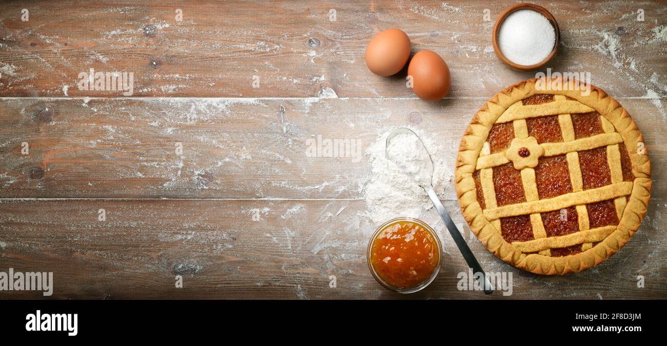 Torte, Crostata, Mürbeteig mit Orangenmarmelade, Mehl, Eiern und Zucker auf Holzteig. Draufsicht, Platz für Text. Stockfoto