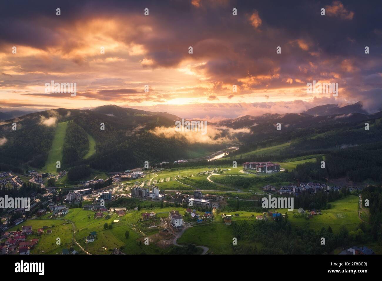 Luftaufnahme des schönen Dorfes in den Karpaten bei Sonnenuntergang im Sommer. Bunte Landschaft mit grünen Wiesen, Häusern, Bäumen, dramatischem Himmel. Oben Stockfoto