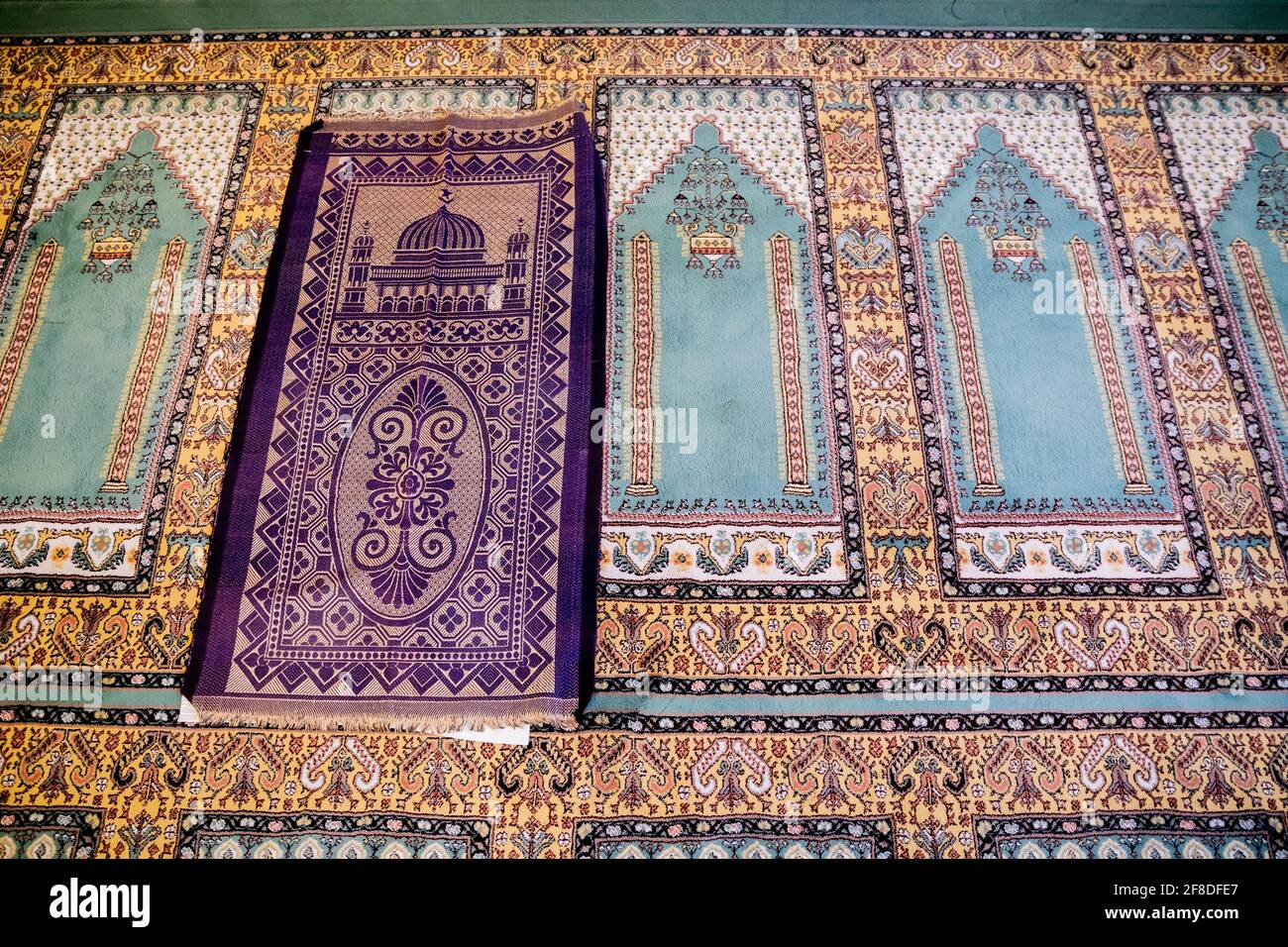 Berlin, Deutschland. April 2021. Auf dem Teppich im Gebetsraum der  Khadija-Moschee der Ahmadiyya-Gemeinde liegt ein Gebetsteppich eines  Gläubigen. Um sich vor Infektionen zu schützen, müssen Gläubige auf ihren  eigenen Teppichen beten. Quelle: