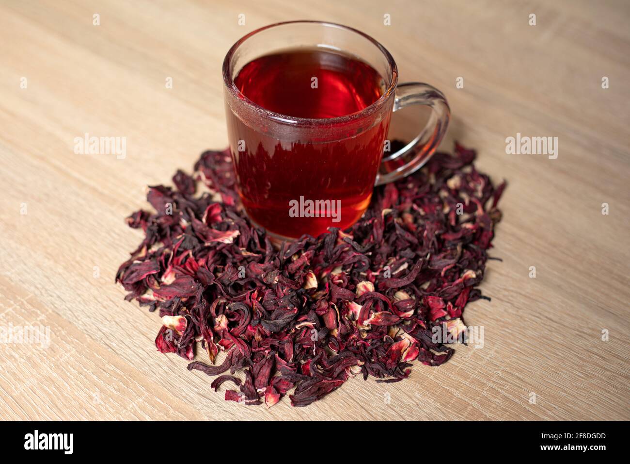 Eine Tasse roten Tee mit Hibiskusblüten auf einem Holztisch Stockfoto