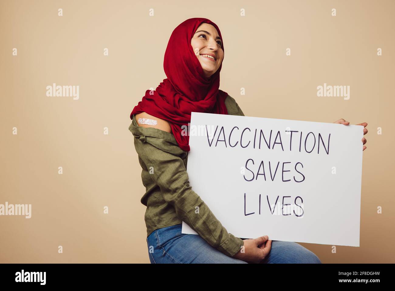 Frau mit Hijab und Banner mit der Aufschrift „Impfung rettet Leben“. Muslimische Frau, nachdem sie Impfungen erhalten hatte, die Menschen dazu erzogen haben, Impfungen zu erhalten, um zu sparen Stockfoto