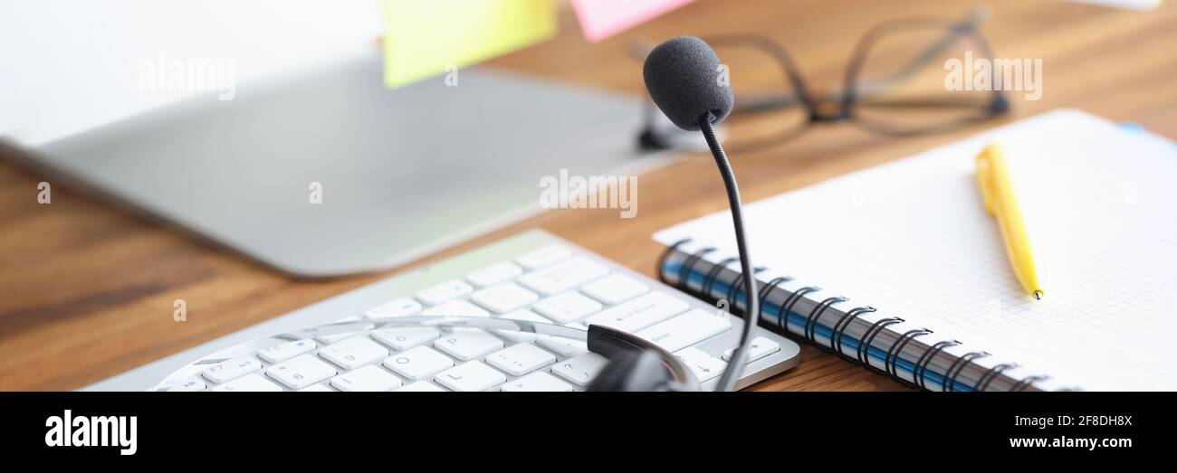 Auf dem Tisch befinden sich Kopfhörer mit Mikrofon und Tastatur, Tagebuch und Stift Stockfoto