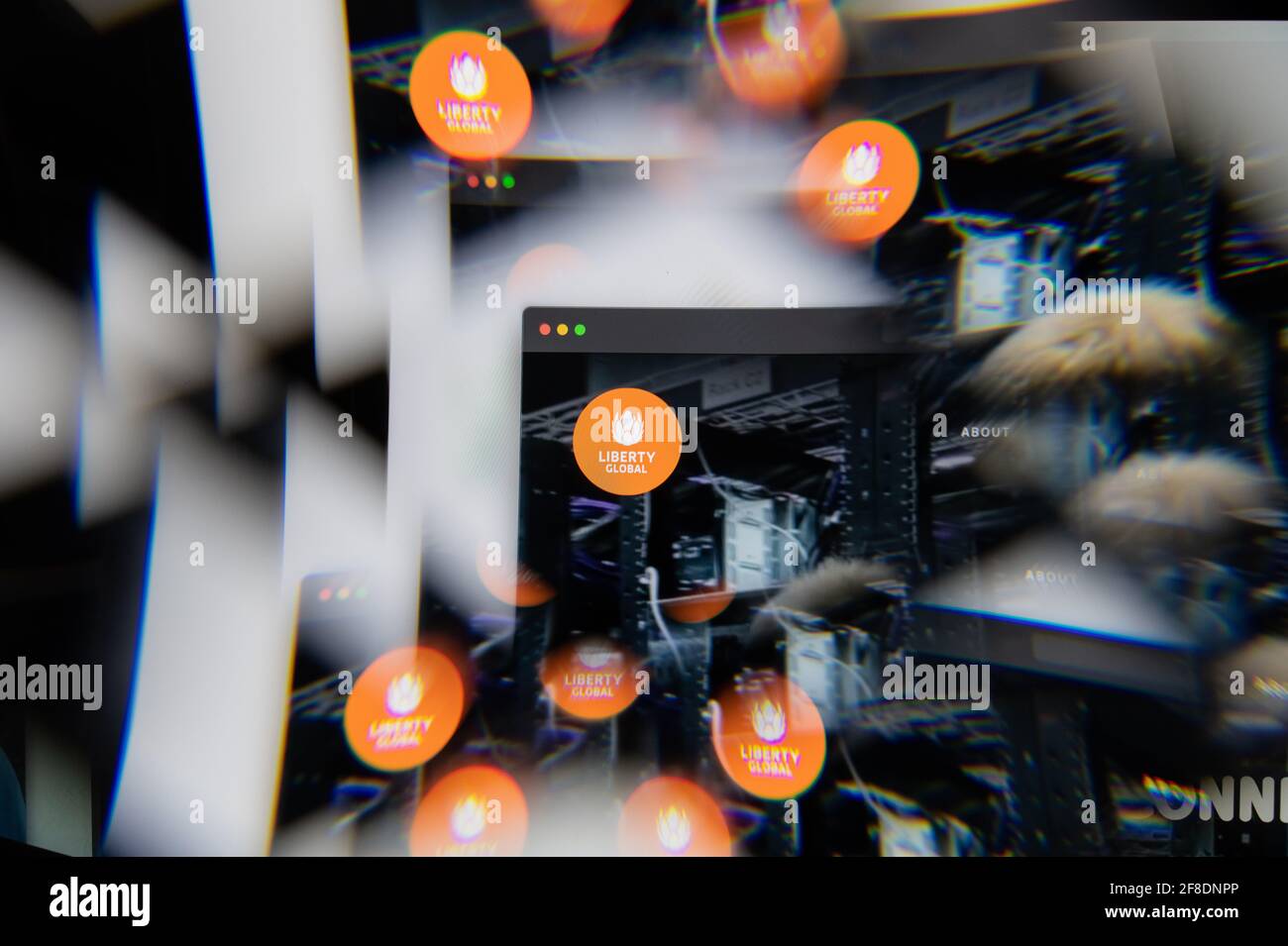 Mailand, Italien - 10. APRIL 2021: Liberty Global Logo auf dem Laptop-Bildschirm durch ein optisches Prisma gesehen. Illustratives redaktionelles Bild von Liberty Global We Stockfoto