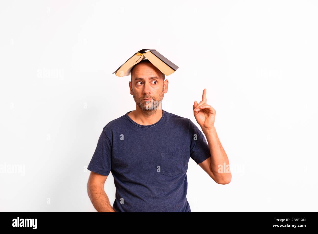 Lustiger Mann mit einem offenen Buch auf dem Kopf denkt und hat Ideen. Stockfoto